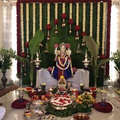 there is a statue in the middle of a table with fruit and flowers on it