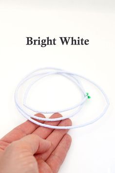 a hand holding two white bracelets on top of a white background with the words bright white