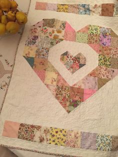 a quilted table topper with a heart on it next to some pears