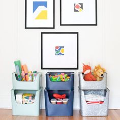 three storage bins with toys in them and pictures on the wall