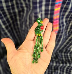 Expertly crafted with intricate beadwork, these Large Beaded Quetzal Earrings embody the beauty and culture of Guatemala. The dainty green and red design adds a stunning touch to any outfit, making them a unique and elegant accessory for any occasion. Embrace the unparalleled craftsmanship and representation of Guatemalan culture with these stylish earrings. Measurements: 4.5 inches long 0.90 inches wide Handwoven Green Jewelry For Festival, Green Handwoven Jewelry For Festival, Traditional Green Handwoven Beaded Necklace, Green Handwoven Beaded Necklace For Gifting, Green Handwoven Beaded Necklace For Gift, Traditional Dangle Jewelry With Bead Caps, Green Dangle Jewelry With Bead Caps, Traditional Green Beads For Festival, Green Bohemian Handwoven Jewelry