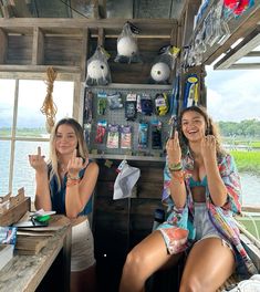 two women sitting at a table with their hands in the air, smiling and waving