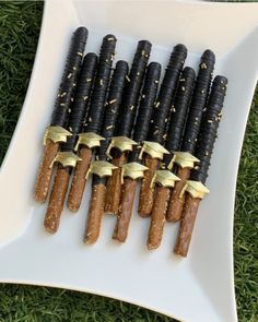 there are many black and gold candy sticks on the white plate with gold trimmings