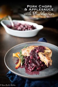 pork chops and applesauce with blueberry sauce on a gray plate next to a white bowl