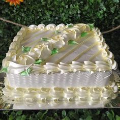 a large white cake sitting on top of a table next to a flowery bush