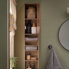 an open cabinet in the corner of a bathroom next to a towel rack and toiletries