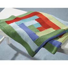 a multicolored blanket sitting on top of a white chair