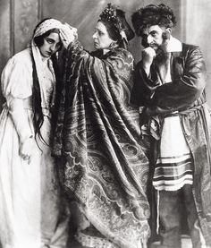 an old black and white photo of two people dressed in historical clothing, one holding the other's head