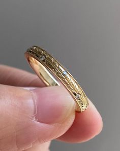 a close up of a person's hand holding a gold ring with diamond accents