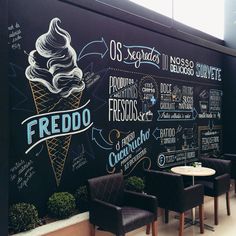 an ice cream parlor with chalk drawings on the wall and chairs in front of it