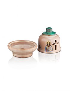 a small wooden bowl with the image of jesus and mary on it, sitting next to a ceramic salt shaker