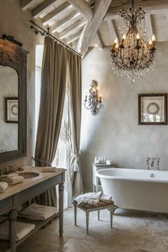 a bathroom with a tub, chandelier and two sinks