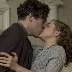 a man and woman kissing each other in front of a door with an open book