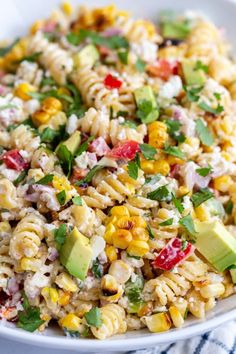 a white bowl filled with pasta salad and topped with avocado