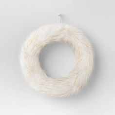 a white fur wreath hanging on a wall in front of a gray background with a silver chain