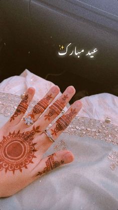 a woman's hand painted with henna on top of a white cloth covered car seat