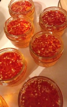 four jars filled with red food sitting on top of a white tablecloth covered counter