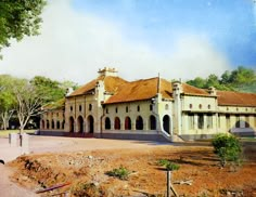 an old building in the middle of a dirt lot with trees and bushes around it