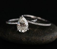 a white diamond ring sitting on top of a rock