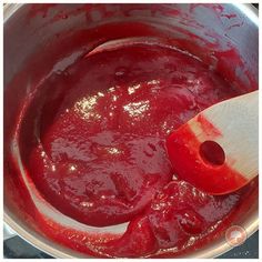 a wooden spoon stirring red sauce in a pot