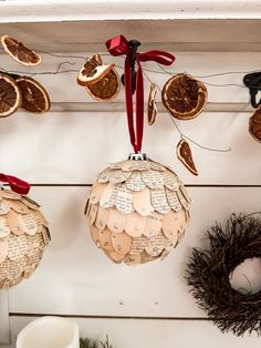 some ornaments are hanging on the wall with red ribbon and decorations around them is an ornament that has been made out of old book pages