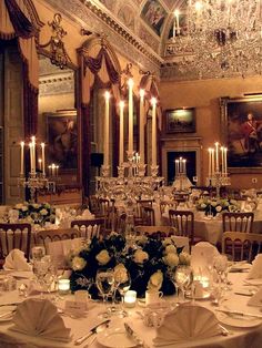 a fancy dining room with chandeliers and white tablecloths set for an event