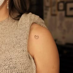 a woman with a small heart tattoo on her left upper arm and right lower arm