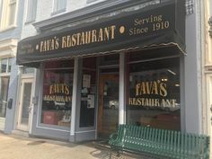 a restaurant with green bench sitting in front of it's storefronts and windows