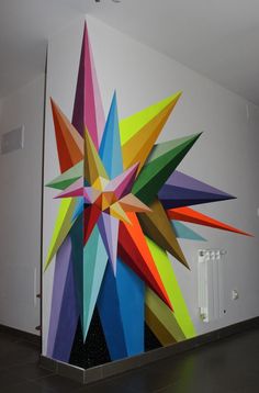 a large multicolored star painted on the side of a white wall next to a radiator