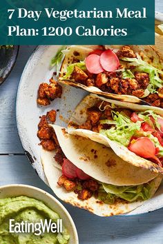 three tacos on a plate with guacamole and salsa