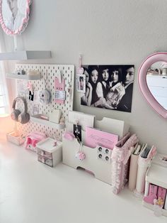 a white desk topped with lots of clutter and pictures next to a pink heart shaped mirror