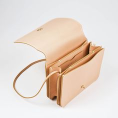 An elevated everyday bag named for the iconic Ray Eames. For the love of design that works, sublime simplicity. The Ray features a custom brass pull release closure, and unfolds to three interior compartments and credit card pocket with our signature curve to organize your essentials. Fully lined leather construction, with a wraparound featherweight strap ideal for layering and ease of wear over the shoulder or across the body. Dimensions: 7.25" x 5.5" x 2" Strap length 46" Vachetta leather is a Modern Flap Bag With Smooth Grain, Rectangular Smooth Grain Flap Bag For Everyday Use, Modern Clutch Shoulder Bag With Interior Card Slots, Modern Flap Bag With Smooth Grain For Everyday Use, Everyday Rectangular Flap Bag With Smooth Grain, Timeless Everyday Bag With Interior Card Slots, Timeless Bags With Interior Card Slots For Everyday Use, Modern Everyday Satchel With Interior Card Slots, Everyday Modern Satchel With Interior Card Slots