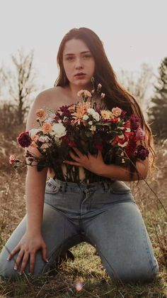 a woman sitting on the ground holding flowers