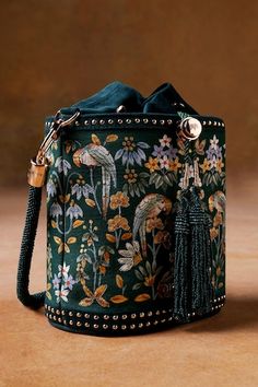 Starling green cylindrical shaped bucket bag with Pichhwai, bird, floral hand painted motifs, zari thread embroidery and metallic stud embellishment. Comes with 2 detachable handles. - Aza Fashions Luxury Bohemian Bags With Embellishments, Cheap Bohemian Bags With Floral Embroidery, Luxury Traditional Shoulder Bag With Zari Work, Luxury Floral Embroidery Bags For Festive Season, Cheap Embroidered Women's Bags, Luxury Bohemian Hand Embellished Bags, Luxury Floral Embroidery Bags For Women, Luxury Bags With Intricate Embroidery For Festivals, Luxury Embroidered Bags For Spring