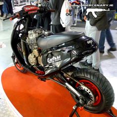 a motorcycle is on display at an indoor event with other people around it and in the background