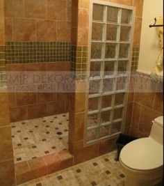 a bathroom with tiled walls and a glass shower door in the corner, next to a toilet