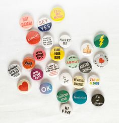 a bunch of buttons with different sayings on them sitting next to each other in front of a white background