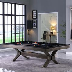 a pool table in a living room with large windows