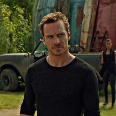 a man in black shirt standing next to a truck