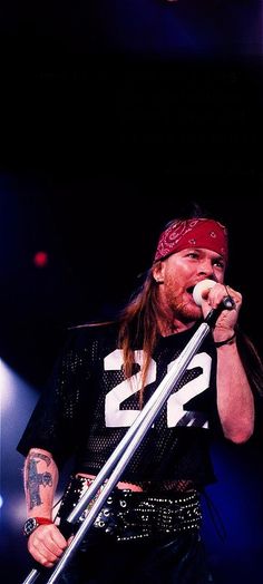 a man with long hair and bandana holding a microphone in front of his face