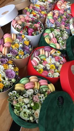 there are many different colored donuts on the table with flowers in them and one has a green hat