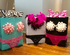 three gift bags decorated with pink, white and black bows are sitting on the floor