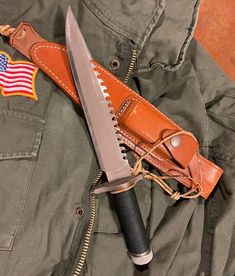 a large knife laying on top of a brown leather case next to an american flag patch