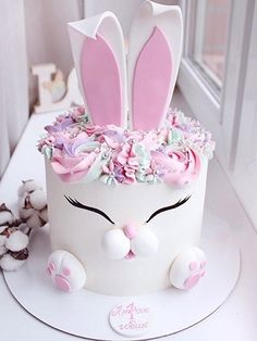 a white cake with pink frosting and bunny ears