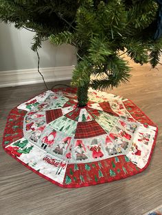 a christmas tree skirt on the floor under a pine tree with red and green trim