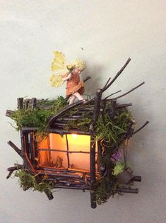 a fairy figurine sitting on top of a house made out of branches and twigs