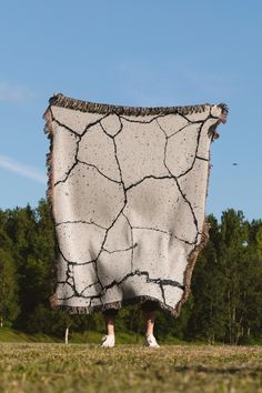 a person standing in the grass holding up a blanket