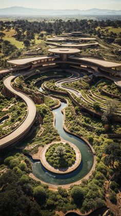 an aerial view of a circular building surrounded by greenery and trees with a river running through the center