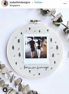 a couple walking down the street in front of a white wall hanging on a wooden frame