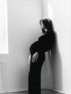 a pregnant woman leaning against a wall